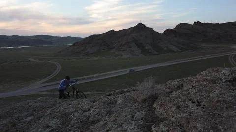 Cyclist on the background of a beautiful sunset climbed the hill with bike Video stock 61642603