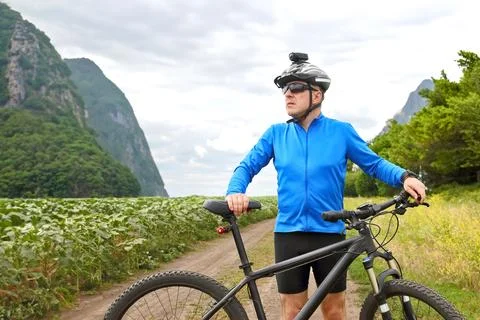 Cyclist with Bicycle standing on field path. Stock Photos