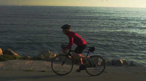 Cyclist Biking by the ocean Stock Footage 62890648