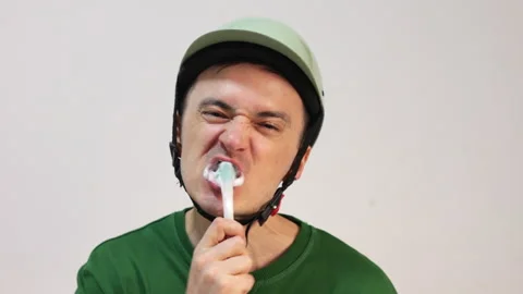 Cyclist brushing teeth wearing helmet on white background Stock Footage 344060278