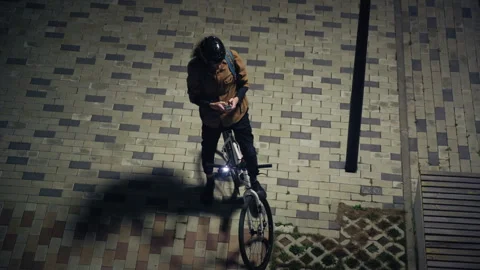 Cyclist checking his smartphone at night 库存影片 345708745