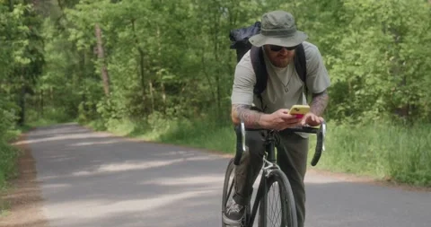 Cyclist checks smartphone while resting on handlebars Stock Footage 311934092