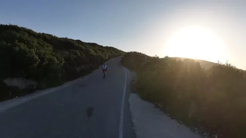 Cyclist climbing empty mountain road at sunset Stock Footage 345945181
