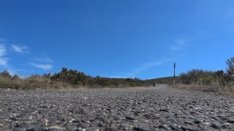 Cyclist coming down the steep slope of a hill covered with dry vegetation Stock Footage 95736557