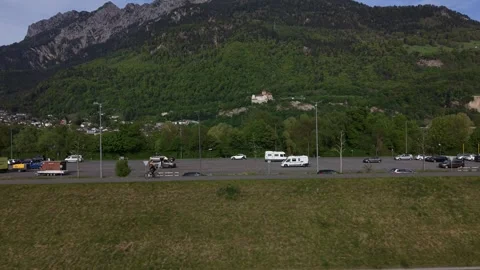 Cyclist commuting alone on rural path with mountains in background Видео 333948922