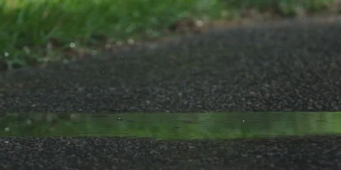 Cyclist cycling through a puddle and splashing water Stock Footage 103747482