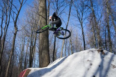 A cyclist does a 360 trick on a springboard in winter. Athlete shows a trick Stock Photos