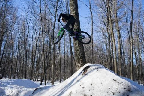 A cyclist does a 360 trick on a springboard in winter. Athlete shows a trick Stock Photos