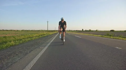 Cyclist doing long training ride on racing bike at sunset Stock Footage 247621697