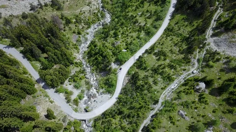 Cyclist going up the mountain with green trees, Bird's eye aerial shot Stock Footage 128704676