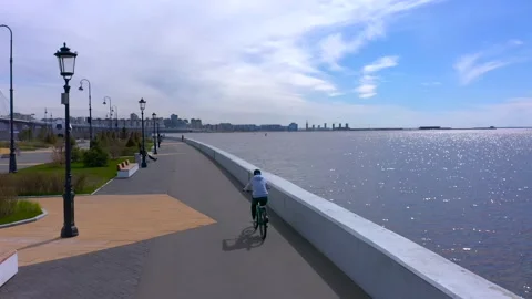 A cyclist in a gray jacket and black pants rides along the promenade Stock-Footage 131416793