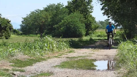 Cyclist has fun passing over a puddle Video stock 116479994
