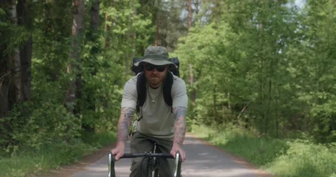 Cyclist looks at camera while riding on forest road Stock Footage 311920384