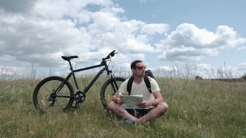 A cyclist looks at the map of the area Stock Footage 246937254
