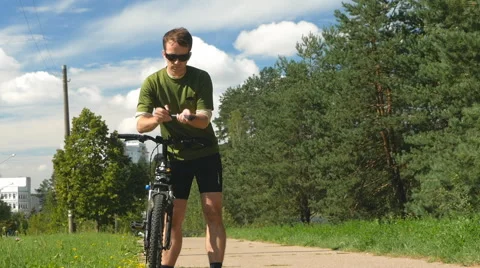 Cyclist man pulls out a folding pump wheel and pumps. Beautiful clouds and dense Stock Footage 66439205