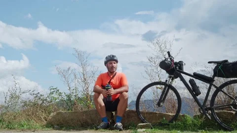Cyclist man resting drinking water. Bikepacking, adventures Stock Footage 164324982