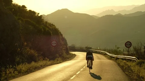 Cyclist on a mountain road at dusk Stock Footage 83399575