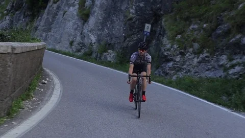 A cyclist passes a mountain bridge Stock Footage 78155651