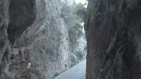 Cyclist passing through road between rock formation Stock Footage 197560935