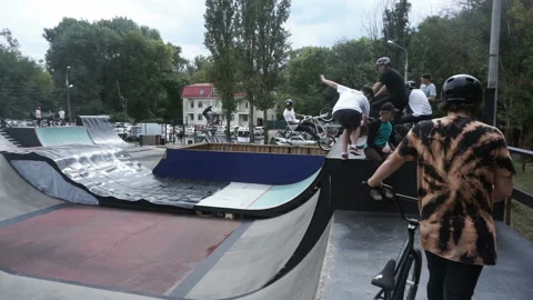 Cyclist performs a stunt on a high slide in a skate park Video stock 103216787