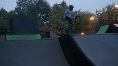 Cyclist performs tricks in the skate park in the evening 库存影片 103213284
