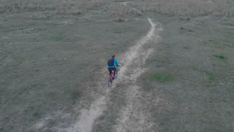 Cyclist with a phone and a backpack goes through the park, shooting from a drone Stock Footage 105968280