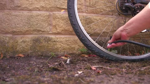 Cyclist pumping flat tyre on bicycle Stock Footage 343382340