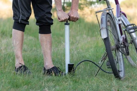 A cyclist pumps air into the wheel using a manual autonomous pump.Inflating.. Stock Photos