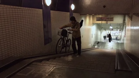 Cyclist pushing bike up a ramp from parking garage in Tokyo Stock Footage