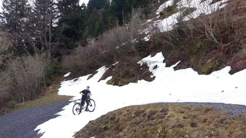 Cyclist pushing bike through deep snow on mountain road Stock Footage 333070497