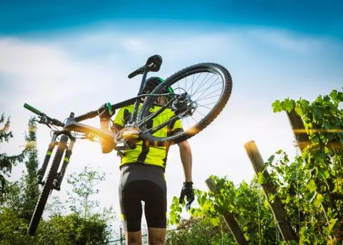 Cyclist raises the mountain bikes on their shoulders. Stock Photos