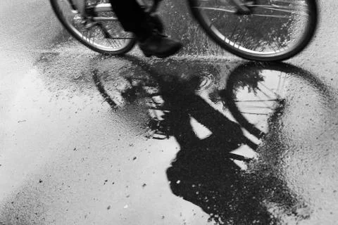 Cyclist reflected in puddle in the rain Stock Photos