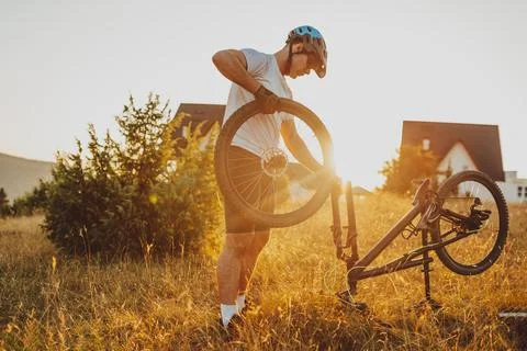 The cyclist repairs and changes the tire on his bike to the mountain at sunse Foto stock