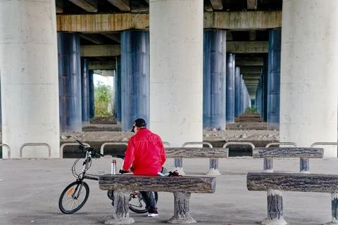 Cyclist Resting on Log Bench Beneath Rows of Pillars at Yong An Bridge 스톡 사진