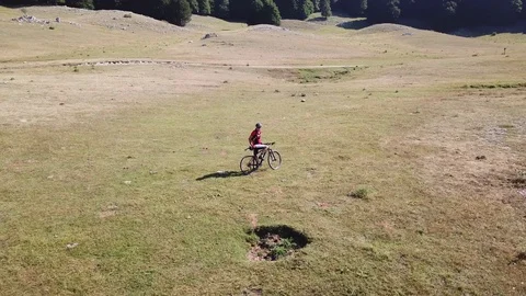 A Cyclist rests in an open mountain valley, aerial view Stock Footage 112994214
