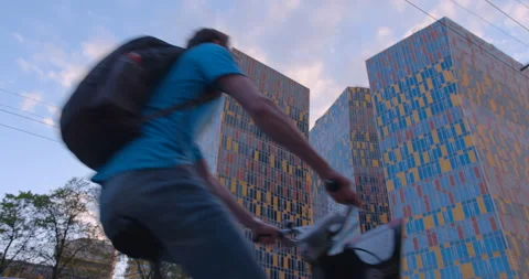 A cyclist rides along a bicycle path in the city, passing by beautiful building Stock Footage 119627975