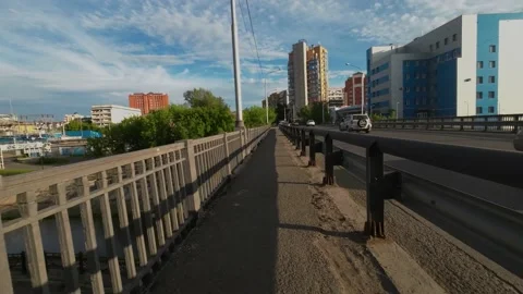 A cyclist rides along the path through the bridge in the summer afternoon Video stock 204937291
