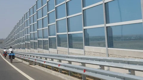 Cyclist rides along the protective screen of the motorway Stock Footage 99060254