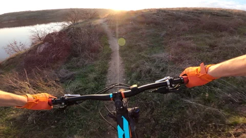 The cyclist rides a difficult rocky path along the river into the sunset. Stock Footage 158245447