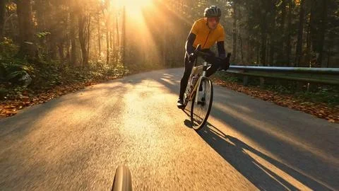 Cyclist rides down a forest road at sunset Foto stock