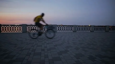 Cyclist rides past on the city waterfront Stock Footage