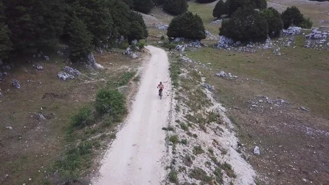 A Cyclist rides on a path in an open mountain valley, aerial view Stock Footage 112993495