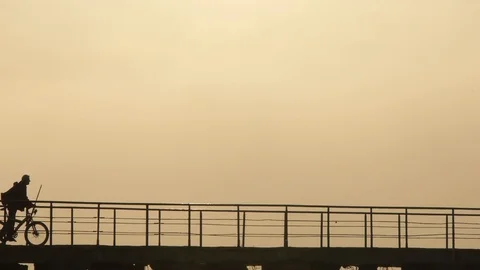 Cyclist rides on the pier in a counterlight Stock Footage 117844928