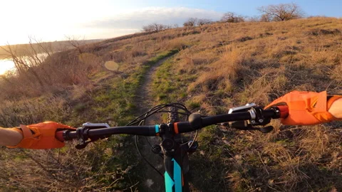 A cyclist rides a technical trail along the river into the sunset. First-person. Stock Footage 158244164
