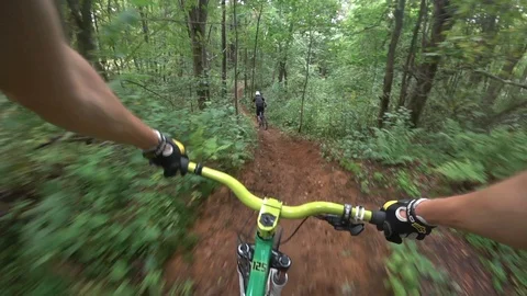 Cyclist rides through the forest for another cyclist, descent from the mountain 動画素材 116489068