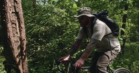 Cyclist rides through forest shadows and sunlight Stock Footage 311920551