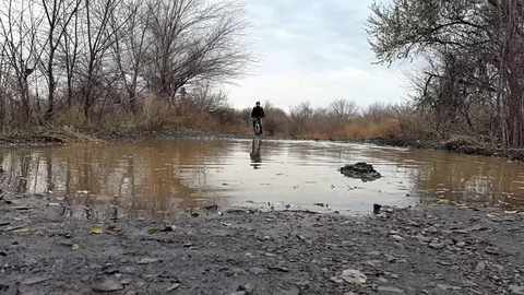 A cyclist rides through a puddle Stock Footage 71651309