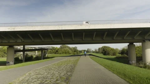 Cyclist rides under a bridge Stock Footage 220203526