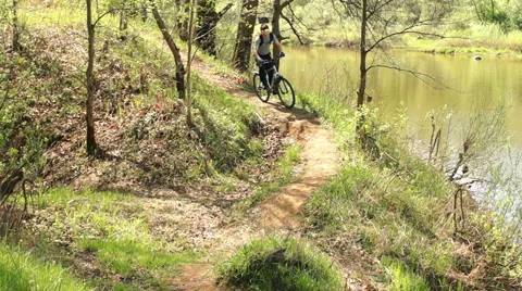 A cyclist riding along a narrow path along the river Video stock 57336543