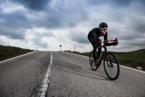 Cyclist riding down the road Stock Photos
